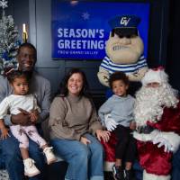 Parents with boy and girl smile with Santa and Louie standing